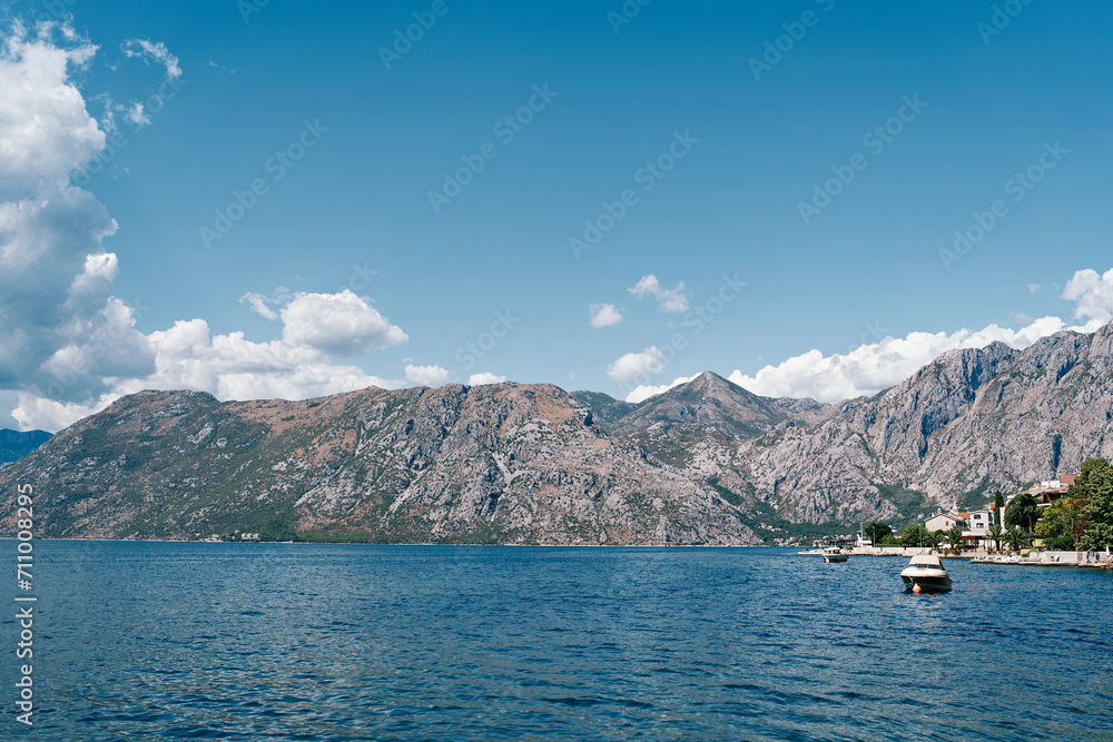 Boat sails along the coast at the foot of the mountain range