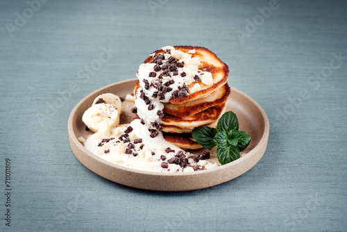 Traditional American Pancakes with banana honey cream and chocolate crumbles served as close-up on a Nordic design plate