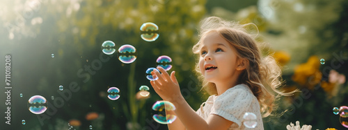 little happy girl playing with soap bubbles photo
