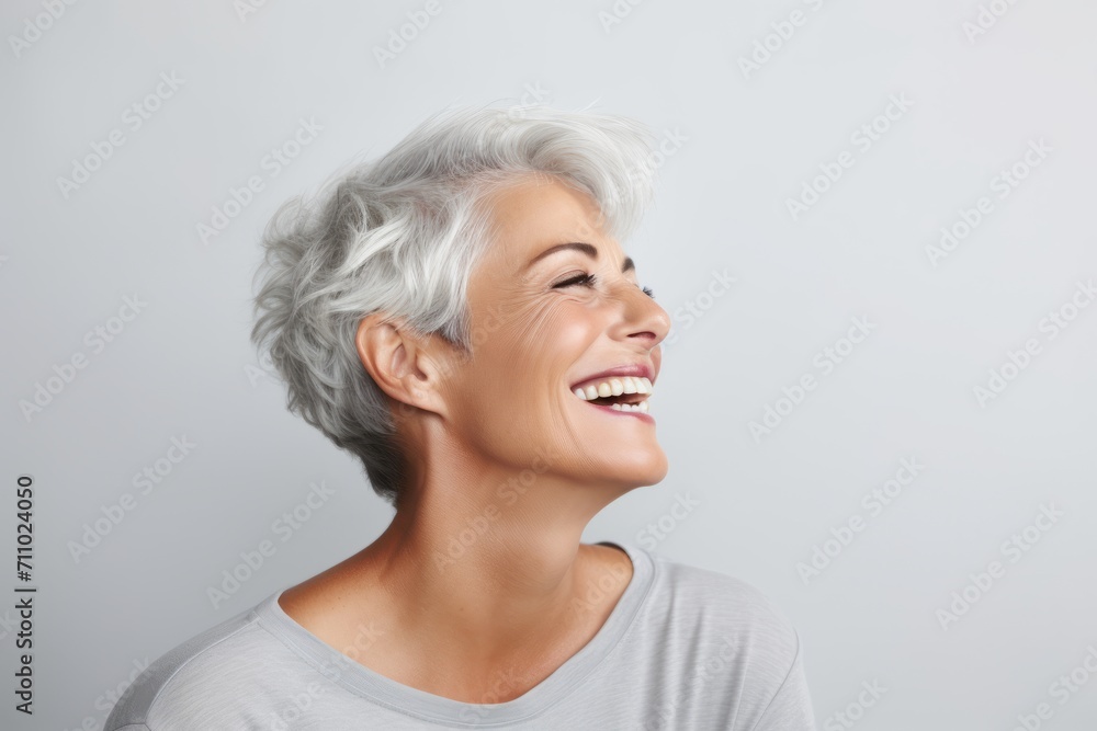 Portrait of a happy senior woman laughing against grey background with copy space Portrait of a happy senior woman laughing against grey background with copy space