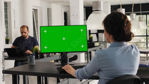 Analyst checks greenscreen desktop on pc, sitting in coworking space at agency office. Company worker examining computer monitor running blank copyspace with mockup screen. Handheld shot.