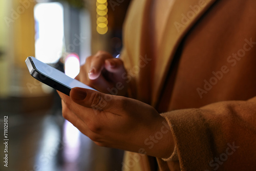Woman using smartphone on night city street, closeup