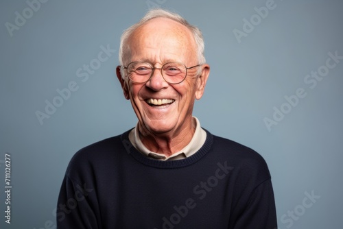 Portrait of a happy senior man with glasses on a gray background © Igor