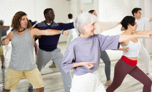 Cheerful old lady learning new modern dance in group dance lesson