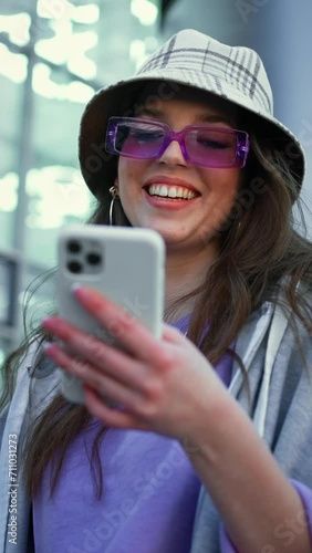Happy woman walking in city street looking into mobile phone smartphone screen