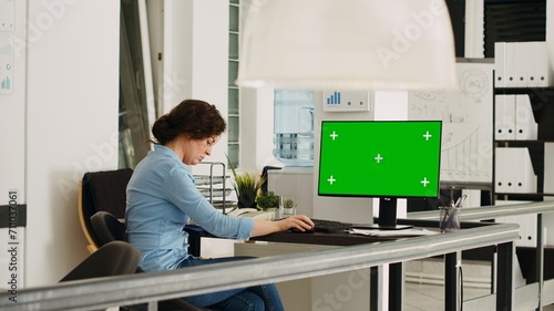 Empty desk with greenscreen layout on computer in coworking space with people solving business operations. Workstation showing computer with isolated copyspace mockup display.