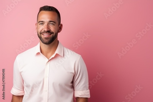 Portrait of a handsome young man smiling at the camera over pink background