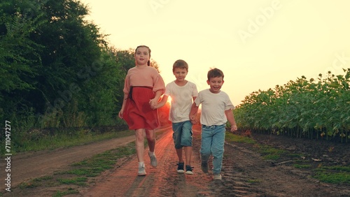 Happy boy, girl running, playing together in nature. Family, children travel in nature. Kids play, run through field of sunflowers, friends run at sunset. Happy Children dream concept. Brother sister