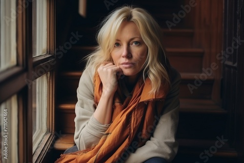 Portrait of a beautiful young woman sitting on the windowsill.