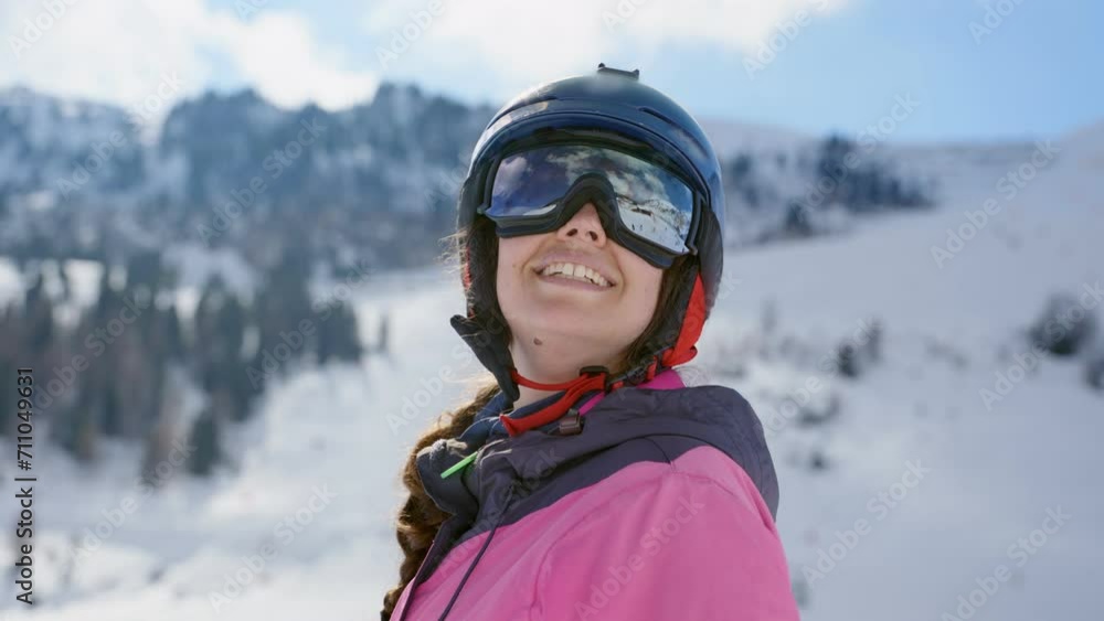 Female skier amazed by snowy mountain view looking around with smile and in awe. Young woman with pink coat looking at mountains in ski resort admiring the view. Enjoying winter vacation outdoors Female skier amazed by snowy mountain view looking around with smile and in awe. Young woman with pink coat looking at mountains in ski resort admiring the view. Enjoying winter vacation outdoors