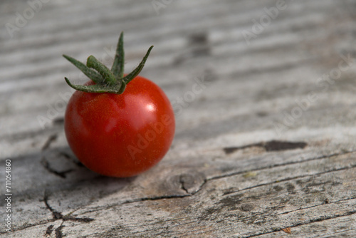 London, UK, 7 January 2024: Red Round Tomato on a dark wooden table  outside 
