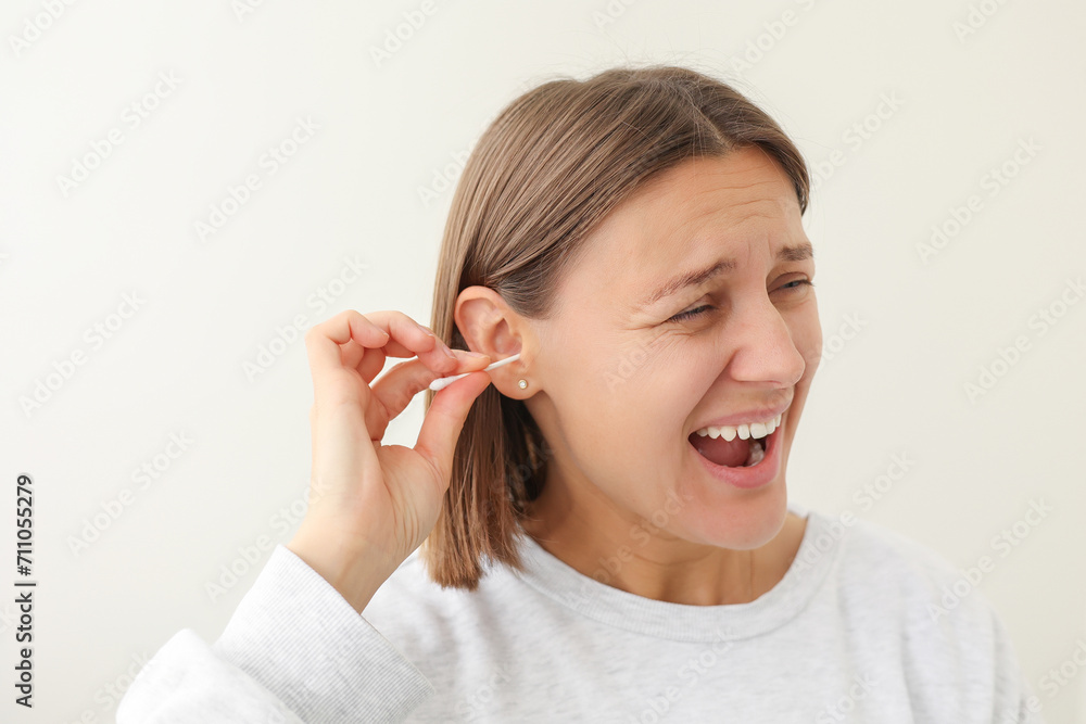 Young woman enjoys to using disposable cotton bud, swab, stick for cleans her auricle earwax on white background. Personal hygiene and care product. Prevention of ear diseases. Sulfur plug removal. Young woman enjoys to using disposable cotton bud, swab, stick for cleans her auricle earwax on white background. Personal hygiene and care product. Prevention of ear diseases. Sulfur plug removal.