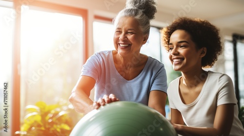 Physical therapist assisting senior woman with exercise ball photo