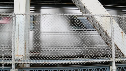 subway train passing behind fence on manhattan bridge (metro heading to brooklyn, new york city) rail commute close up train car (cars passing, man walking)