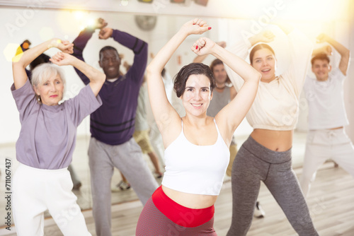 Adult group of people engaged in a dance studio, learn the movements of zumba in a dance lesson