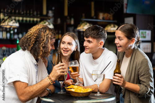 Cheerful young adult friends having fun together in vintage pub  talking and drinking beer at table