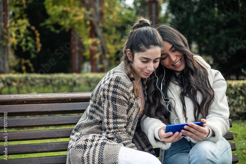 Konstfotografi couple of girls with headphones and smartphone looking screen