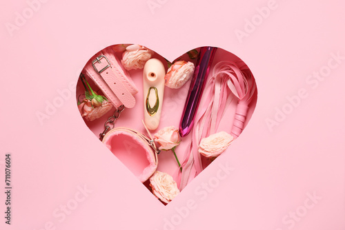 Composition with different sex toys and beautiful rose flowers on pink background
