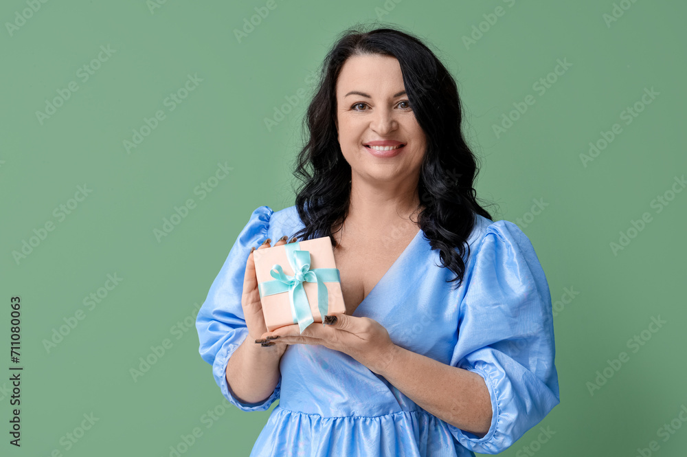 Mature woman with gift box on green background. International Women's Day Mature woman with gift box on green background. International Women's Day