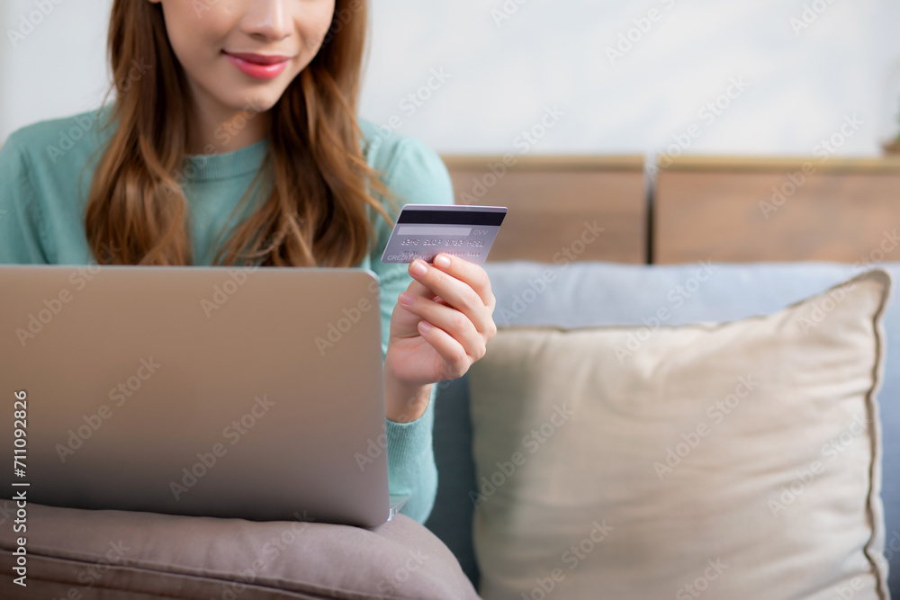 Young asian woman sitting on sofa using laptop computer shopping online with credit card buying to internet, female payment with business on couch, purchase and payment, business and lifestyles. Young asian woman sitting on sofa using laptop computer shopping online with credit card buying to internet, female payment with business on couch, purchase and payment, business and lifestyles.