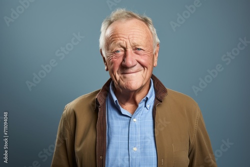 Portrait of a senior man with wrinkles on his face against blue background © Iigo