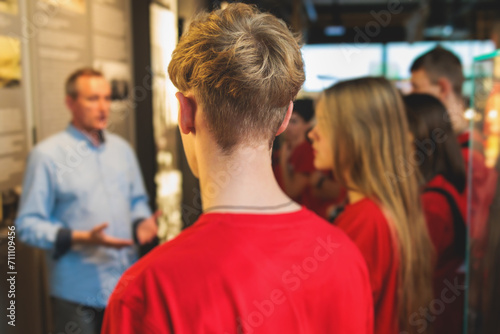 Group of students and school pupils in a science museum exhibition, excursion tour with guide, a docent with a tourist visitors, school field trip, attendees of technical museum exposition gallery