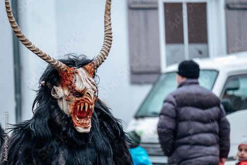 Krampus demon on blurred street background.Carnival processions in Germany. Carnival costumes and characters.Winter costume processions on the streets of Europe.Demon face of Krampus monster. photo