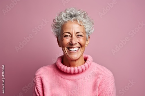 Portrait of a happy senior woman smiling at camera against pink background