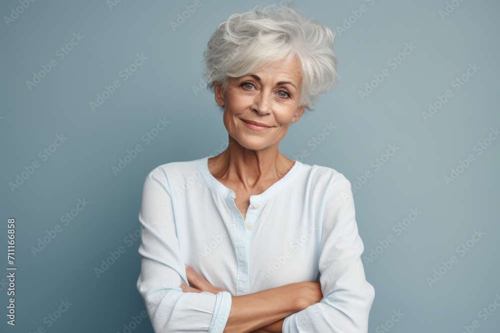 Portrait of smiling senior woman with crossed arms isolated on grey background Portrait of smiling senior woman with crossed arms isolated on grey background
