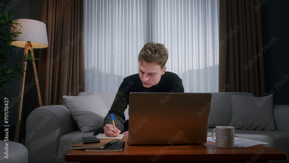 Young blonde man working from home using with laptop while sitting on sofa at home. Focused millennial male looking at laptop, taking note on notebook
Young blonde man working from home using with laptop while sitting on sofa at home. Focused millennial male looking at laptop, taking note on notebook