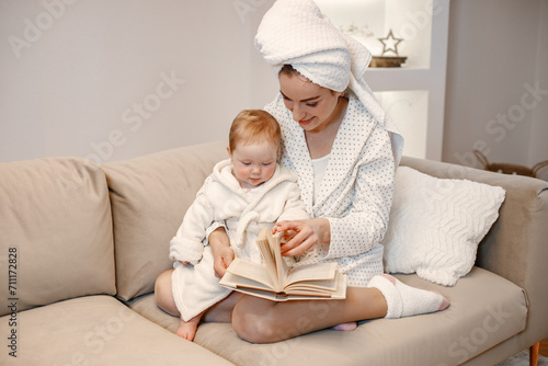 Charming mother and little baby daughter with hair wrapped in towels