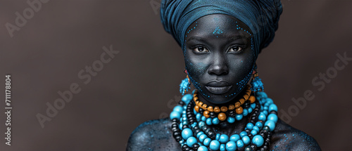 African woman portrait with large ethnic blue necklaces from Africa and traditional turban around her head. Icon of Legacy and ethnic pride of black African people for black history month. Copy space