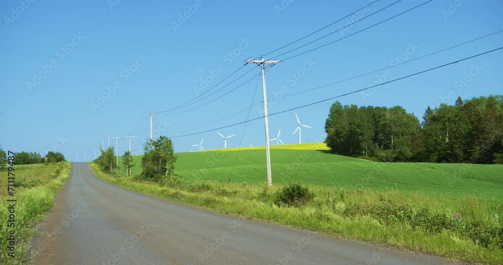 Power line near rural road with wind turbine in the field Power line near rural road with wind turbine in the field