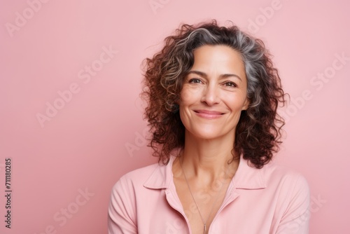 Portrait of smiling mature woman looking at camera over pink background.