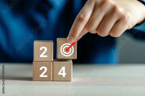 Hand-place wooden cubes with goal icon, Wooden cubes with 2024 and target icon, 2024 goals of a business, starting planning target new year, goal an annual achievement plan.