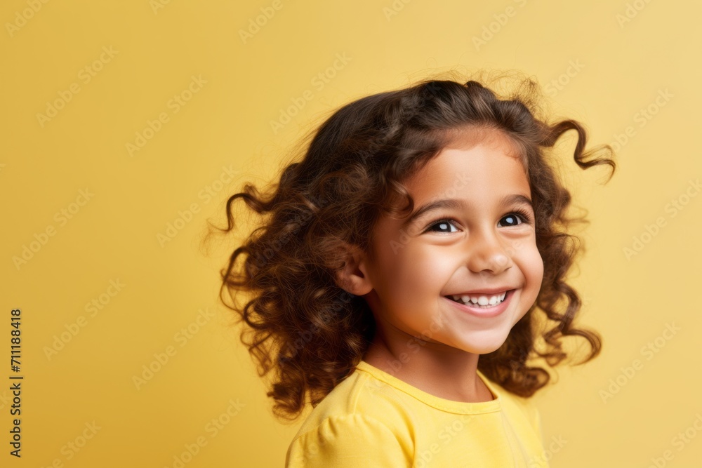 Portrait of a smiling little girl with curly hair over yellow background Portrait of a smiling little girl with curly hair over yellow background