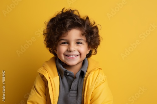 Portrait of a smiling little boy in a yellow jacket on a yellow background © Inigo