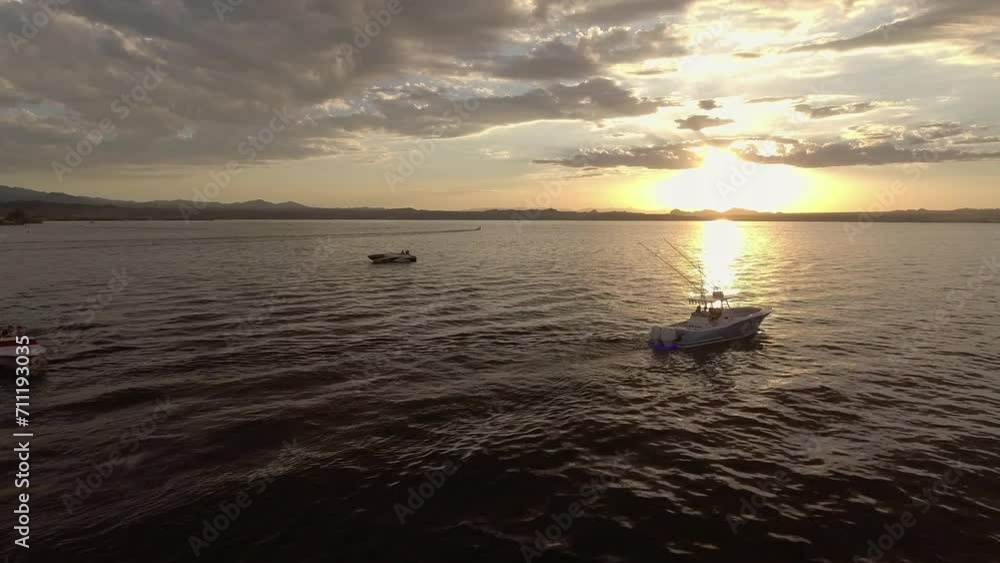 Aerial: Drone Panning Shot Of People Exploring Sea In Motorboat Under Cloudy Sky At Sunset - Magdalena Bay, Mexico