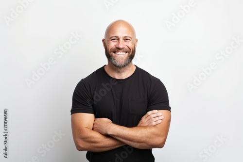 Fotografering Portrait of a happy bald man in a black t-shirt with crossed arms