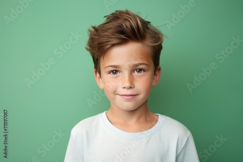 Portrait of a cute little boy with a funny hairstyle on a green background