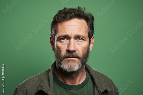 Portrait of mature man with beard and mustache on green background. © Inigo