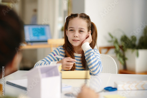 School girl writing letters in copybook when sitting at desk in class