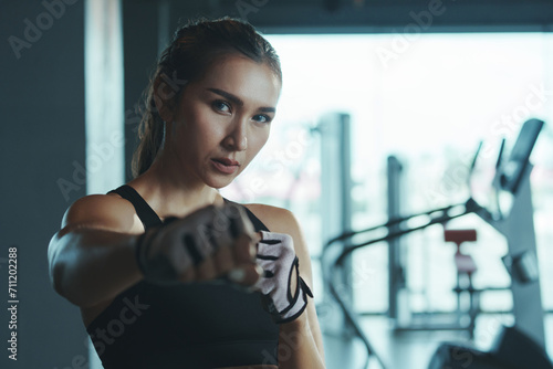 Sporty woman wearing boxing gloves poses in fighting position looking at camera.