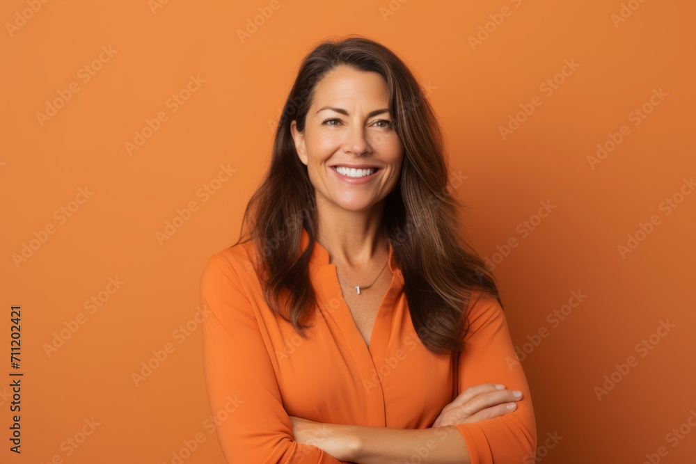 Portrait of smiling woman with crossed arms looking at camera over orange background Portrait of smiling woman with crossed arms looking at camera over orange background