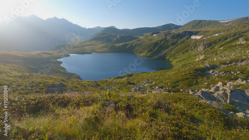 Beautiful blue lake in the mountains amongst rocks and grass. Dawn in the mountains. Hiking in the mountains in summer.