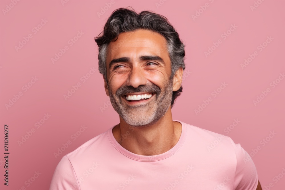 Portrait of a happy mature man smiling and looking at the camera against pink background Portrait of a happy mature man smiling and looking at the camera against pink background