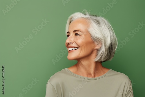 Happy senior woman. Cheerful mature woman looking at camera and smiling while standing against green background