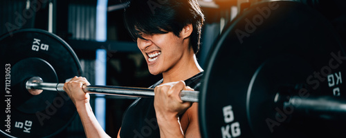 A fit and strong man with a muscular body, lifting weights and holding a barbell for a functional training and endurance workout in the gym. power lifting training concept photo