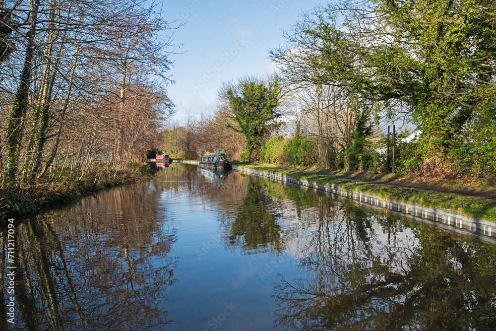 Narrowboat on a British canal in rural setting Narrowboat on a British canal in rural setting