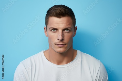 Portrait of young handsome man in white t-shirt on blue background © Inigo